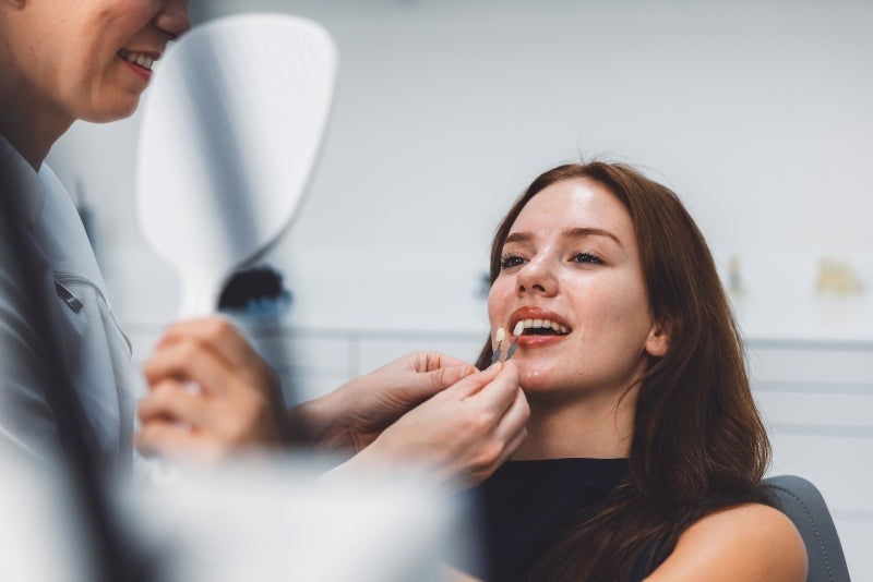 Young woman checking composite dental veneers with the dentist in Phoenix, AZ