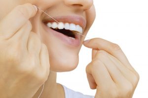 women cleaning her teeth with thread